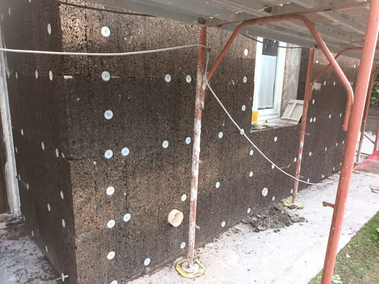 Pannelli di sughero espanso per cappotto termico, fissati con dischi bianchi. Lavori in corso su un edificio.