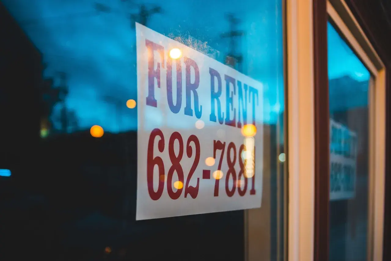 Szyba z napisem "FOR RENT" i numerem telefonu. Czy to dzierżawa, czy najem? Zadzwoń i się dowiedz!