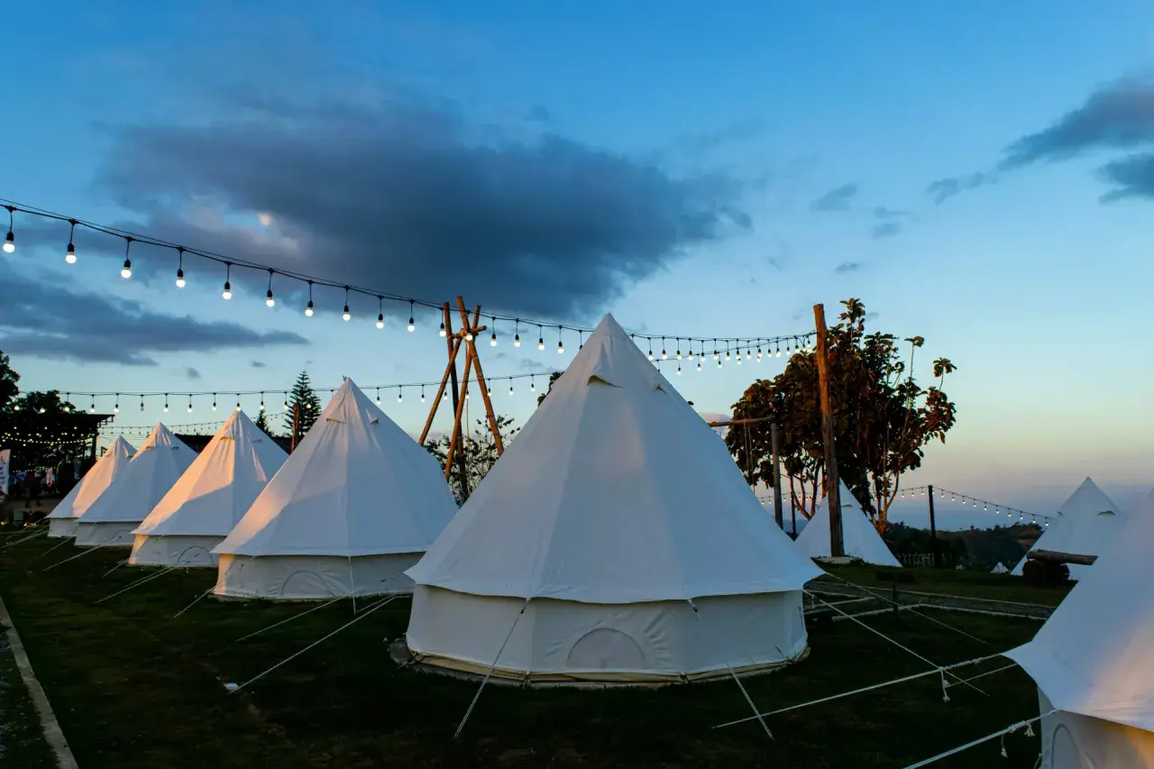 Nocleg w namiotach typu dzwon, oświetlonych girlandami. To właśnie glamping co to – luksusowy kemping w otoczeniu natury.