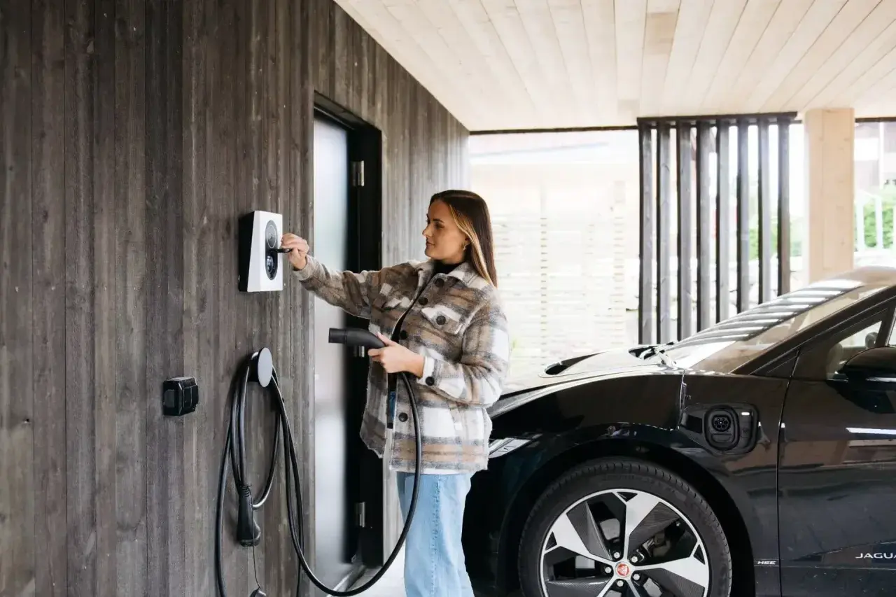 Kvinna laddar elbil vid laddbox. Frågan "hur lång tid tar det att ladda en elbil 22kw" är relevant här.