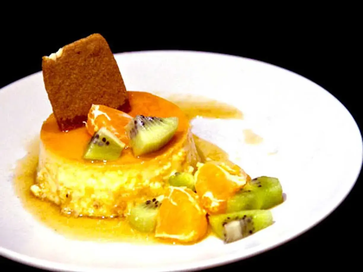En krämig creme caramel med frukt och en kexbit. Perfekt för ett somrigt recept.