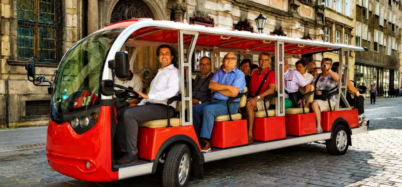 Eine Gruppe von Touristen genießt eine entspannte Stadtrundfahrt in Breslau mit einem roten Elektro-Tourbus.