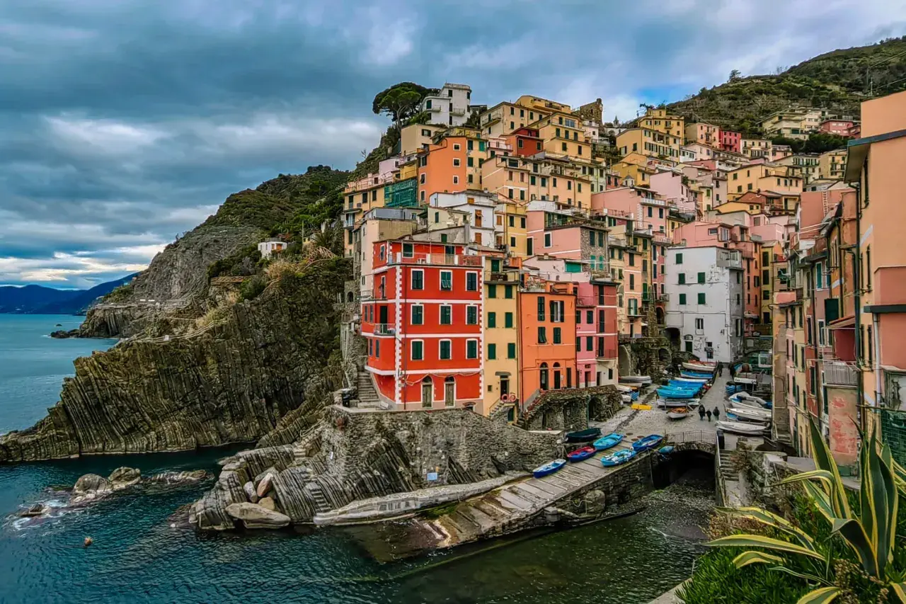 Kolorowe **miasta Cinque Terre** wznoszą się na skalistym wybrzeżu Ligurii. Domy przytulone do klifu, łodzie przy brzegu.
