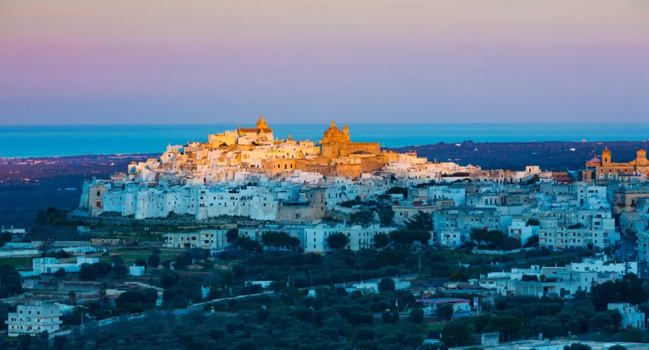 Ostuni, the "White City," glows at sunset, a beautiful destination near the closest airport to Puglia, Italy.