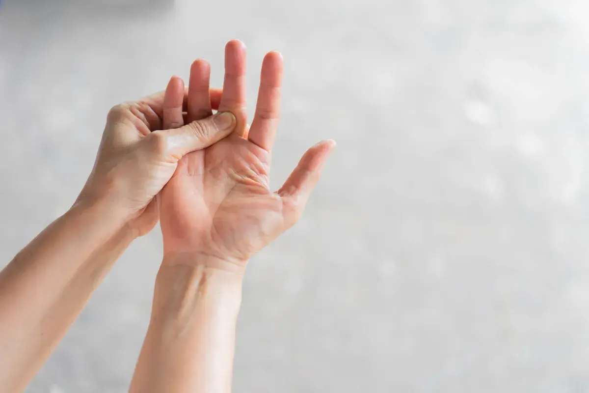 Mani che si massaggiano le dita, un gesto per alleviare il formicolio nel corpo causato dallo stress.