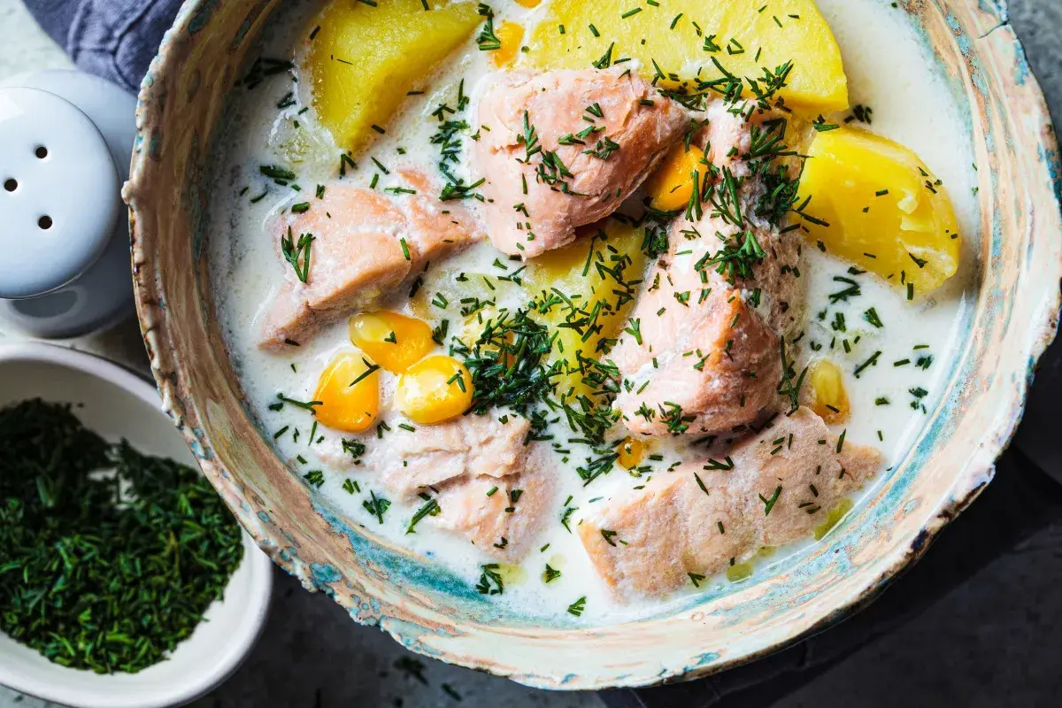 Łosoś w śmietanowym sosie z ziemniakami i kukurydzą, posypany koperkiem. Danie wygląda apetycznie, choć norwegia ceny w restauracjach mogą być wysokie.