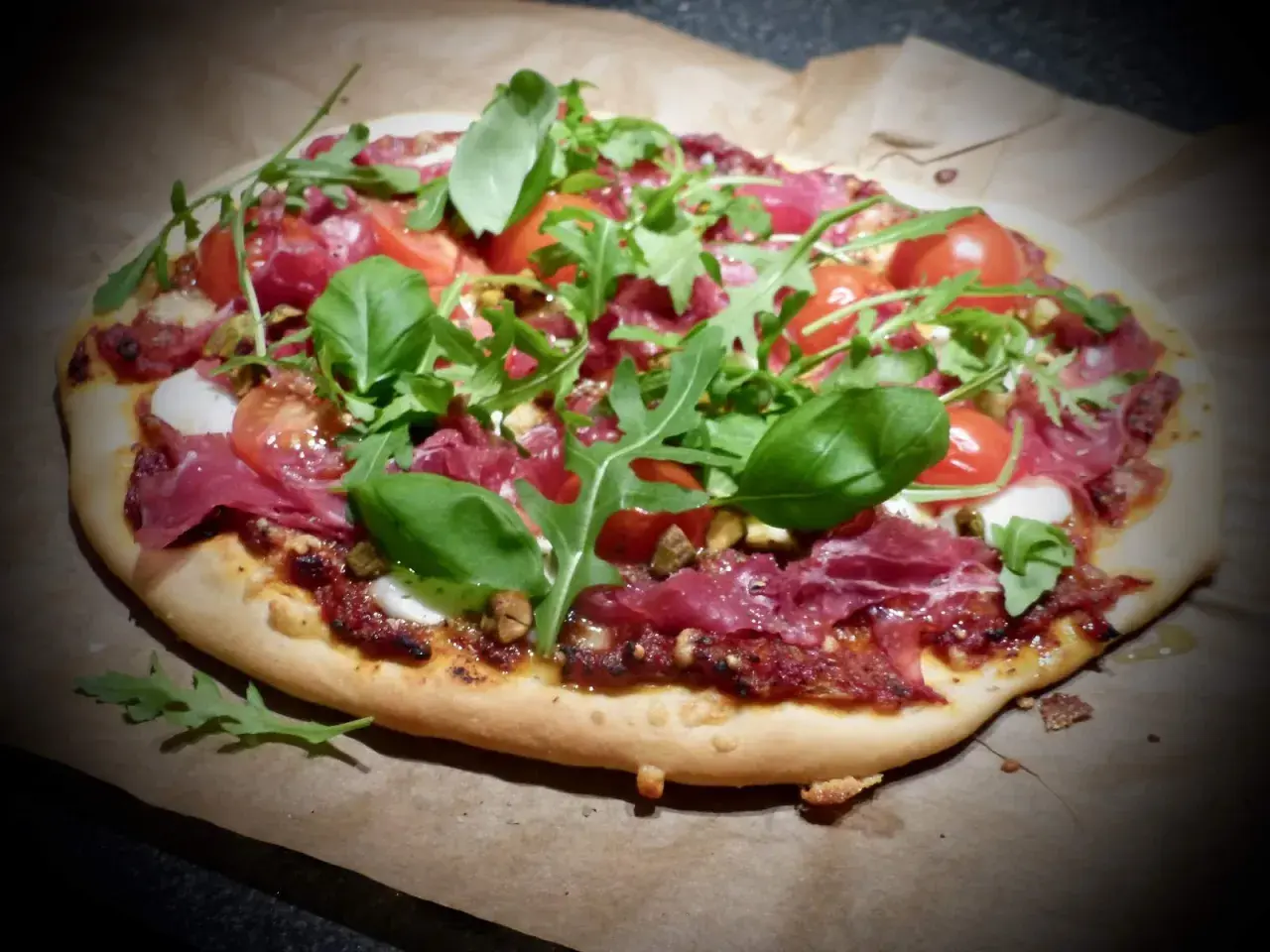 En läcker bresaola pizza med körsbärstomater, ruccola och färsk basilika.