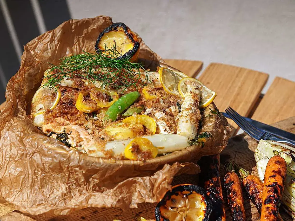 Fisk i folie med citron, dill och grönsaker, serverad med grillade morötter och fänkål.