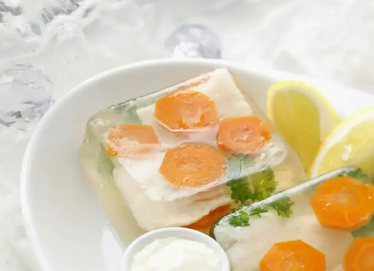 Elegancka ryba w galarecie z marchewką i natką pietruszki, podana z cytryną i chrzanem.
