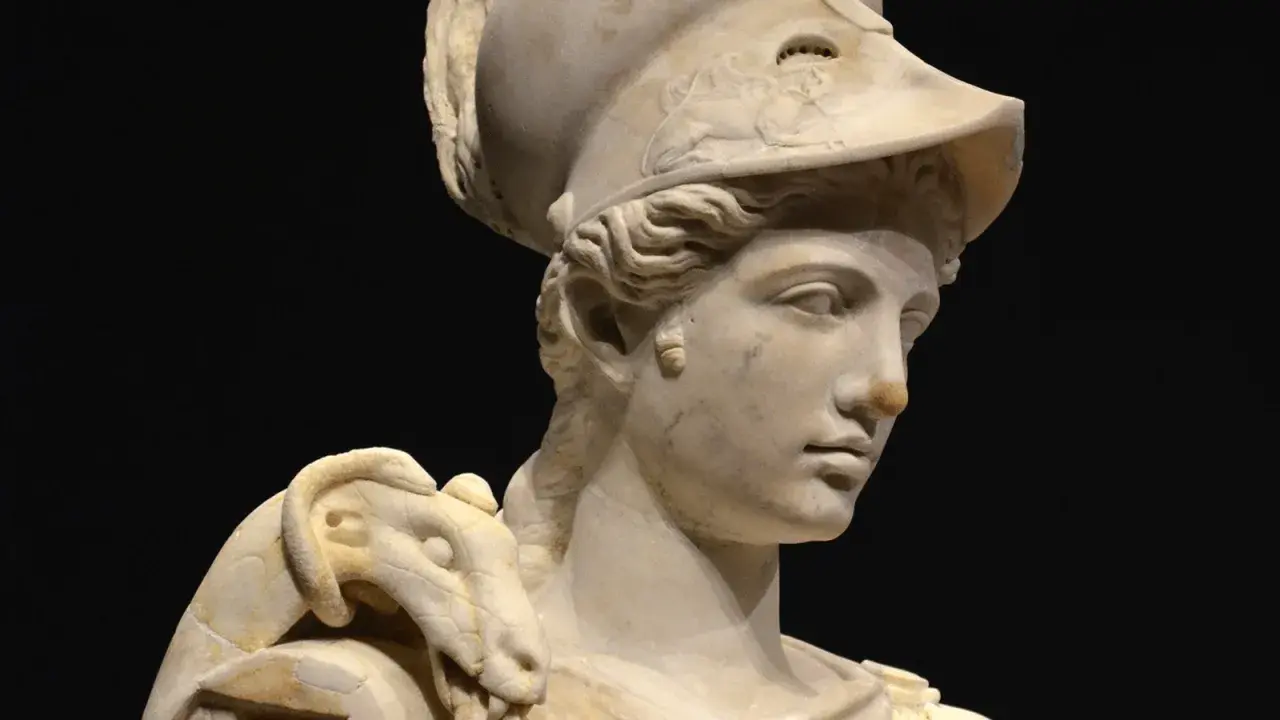 Buste en marbre d'Athéna, déesse guerrière, portant un casque orné d'un serpent. La sculpture, d'une grande finesse, capture la noblesse de la déesse.