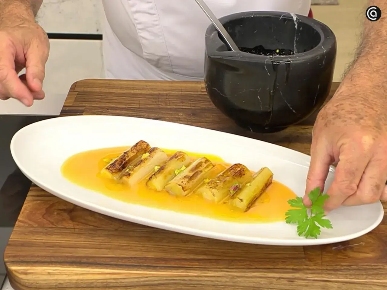 Puerros a la plancha, dorados y tiernos, bañados en una salsa dorada y decorados con perejil fresco.