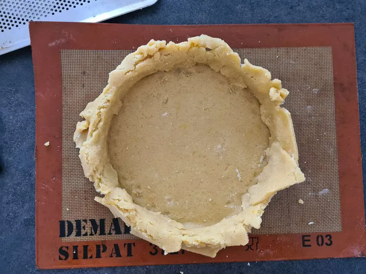 Pâte à gâteau basque prête à être garnie, posée sur un tapis Silpat.