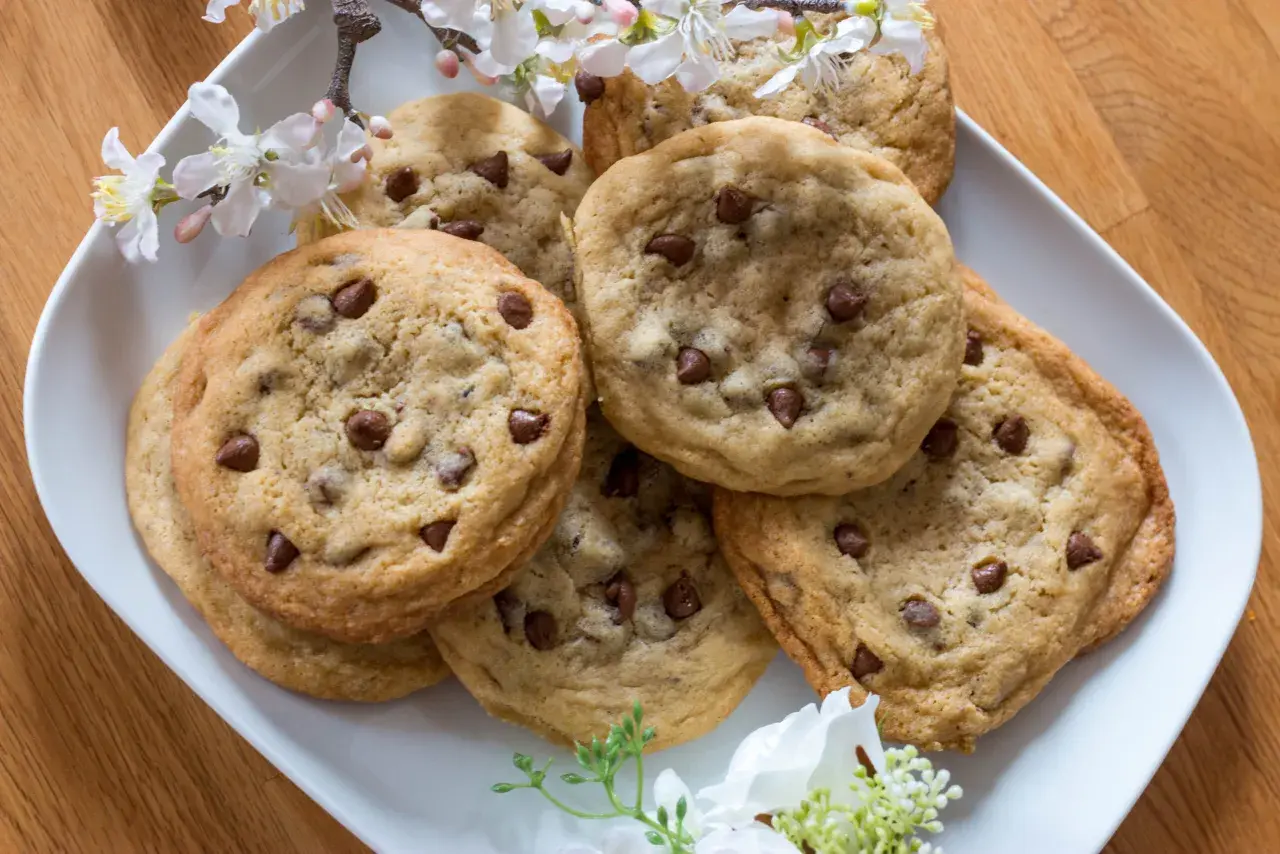 Ein Teller mit frisch gebackenen Schoko Cookies, verziert mit zarten Blüten.