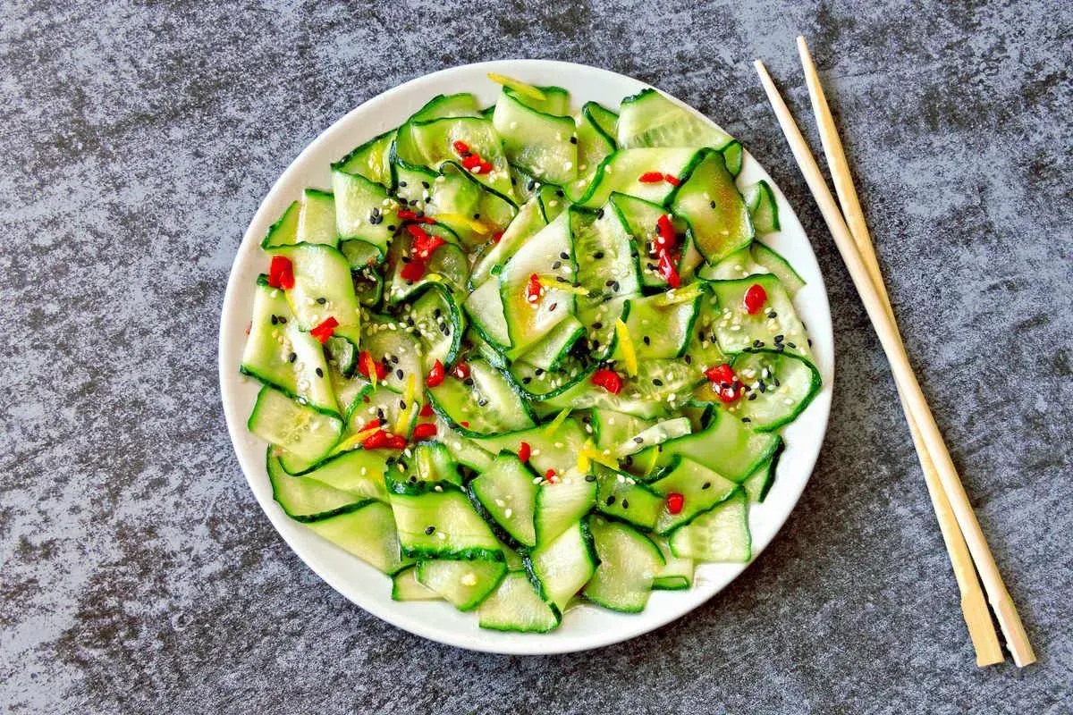 Insalata di cetrioli affettati sottili, condita con peperoncino, sesamo e scorza di limone. Un'idea fresca per le tue ricette con cetrioli.