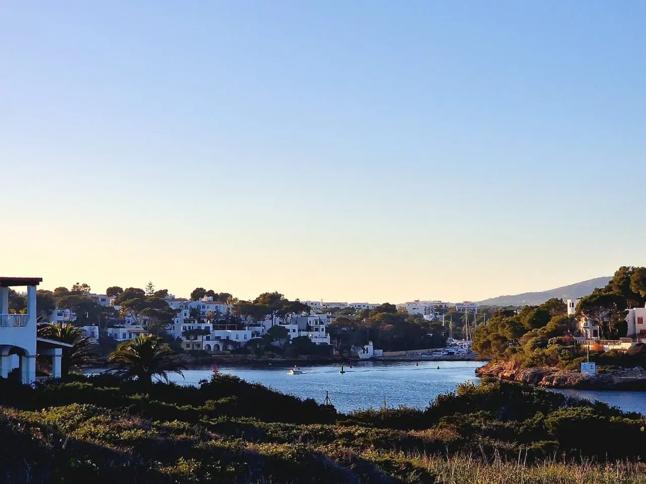 Blick auf die malerische cala d'or altstadt mit weißen Häusern, grünen Pinien und dem blauen Meer.