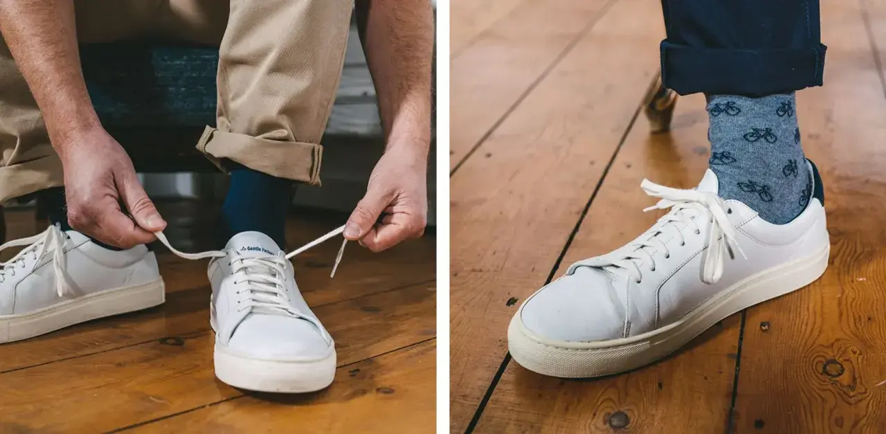 Un homme ajuste sa tenue avec une chaussure blanche homme, des chaussettes à vélos et un pantalon beige retroussé.