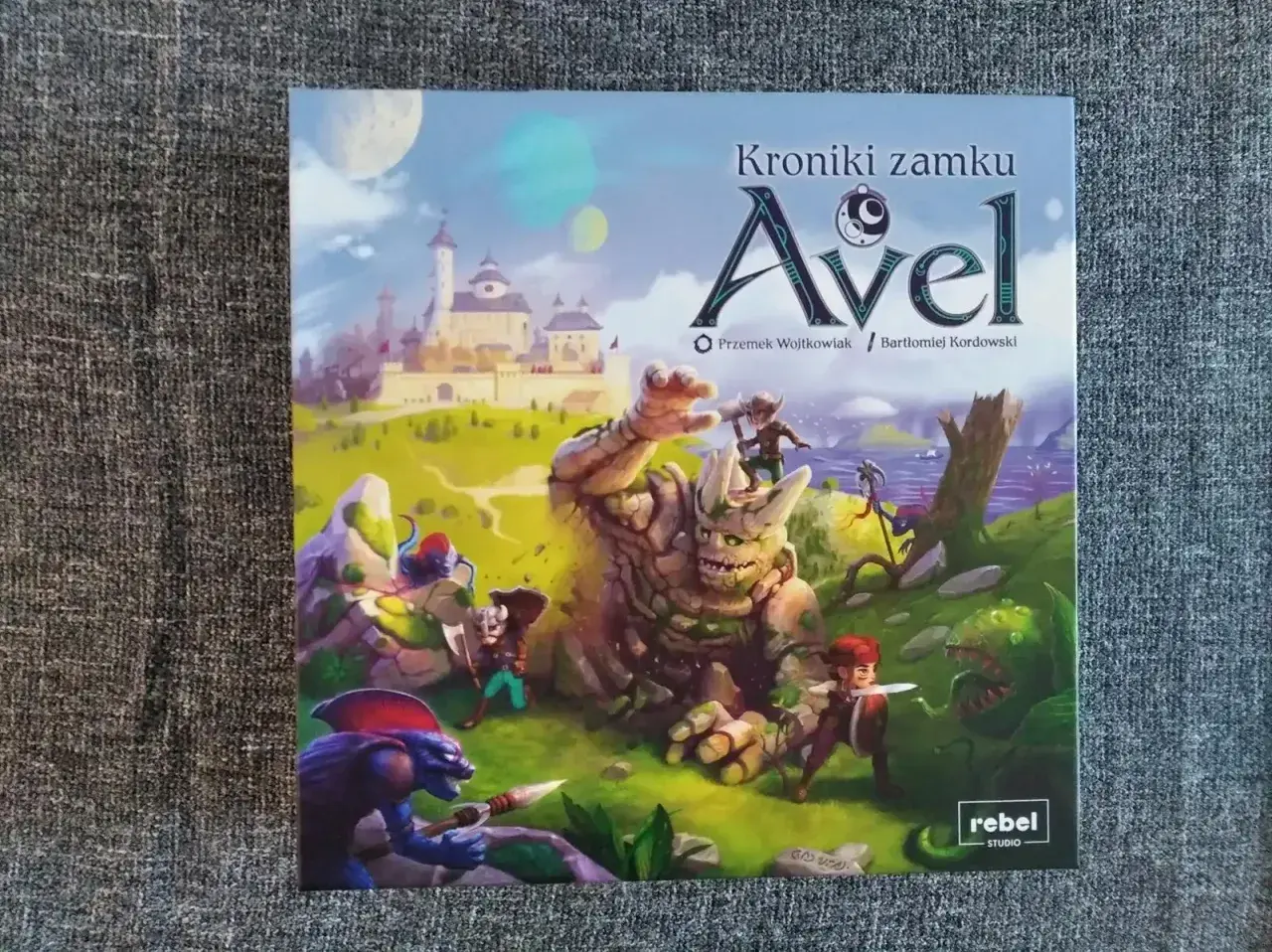 Avel gra: Kroniki zamku Avel. Gigantyczny kamienny golem walczy z bohaterami u stóp magicznego zamku.