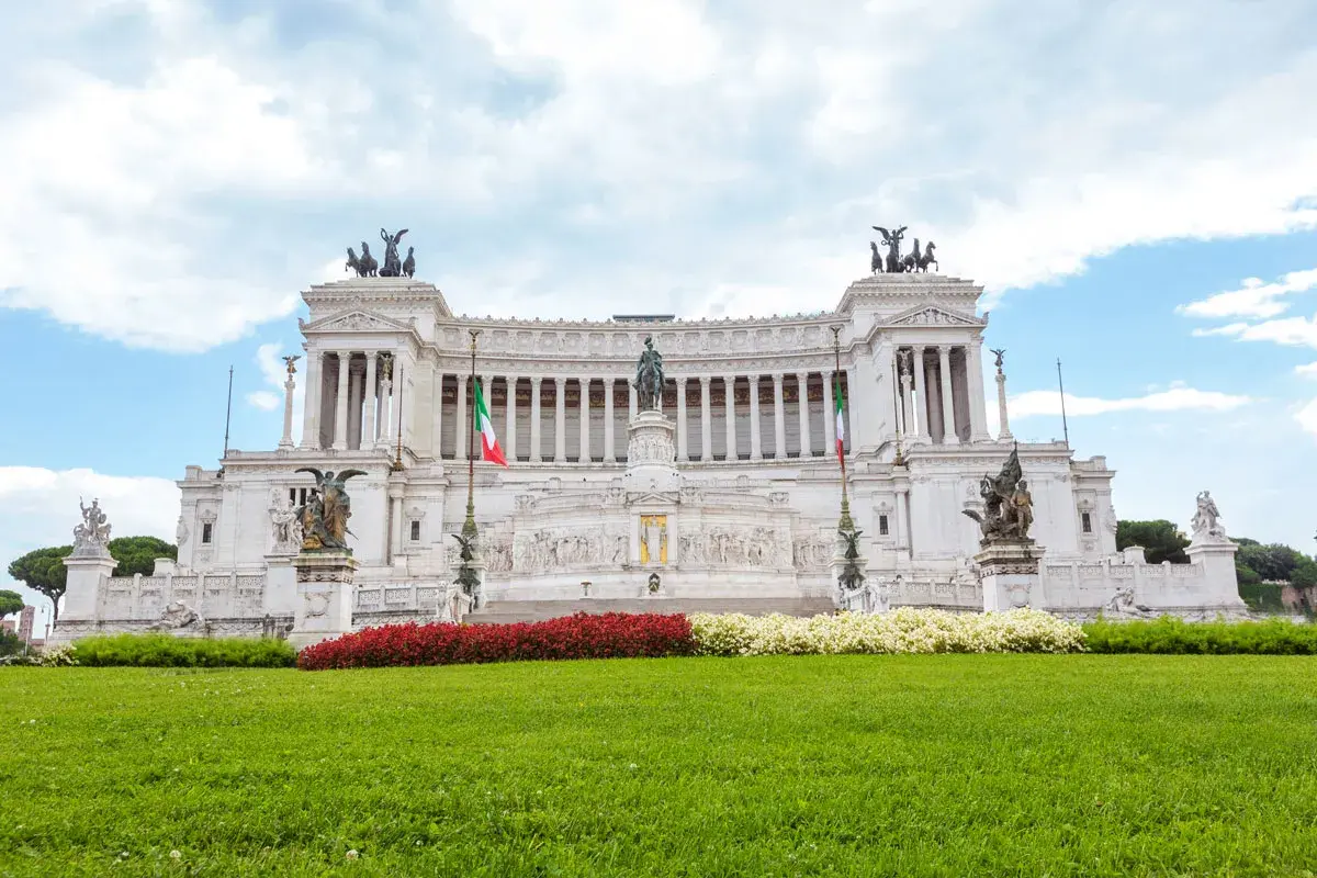 Imponente altare della patria statua equestre al centro, circondato da colonne, bandiere italiane e sculture.