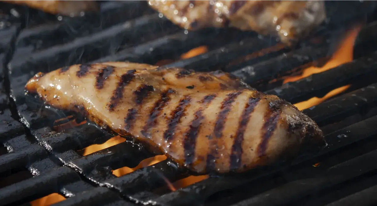 Saftig kycklingfilé med fina grillränder som grillas över öppen eld.