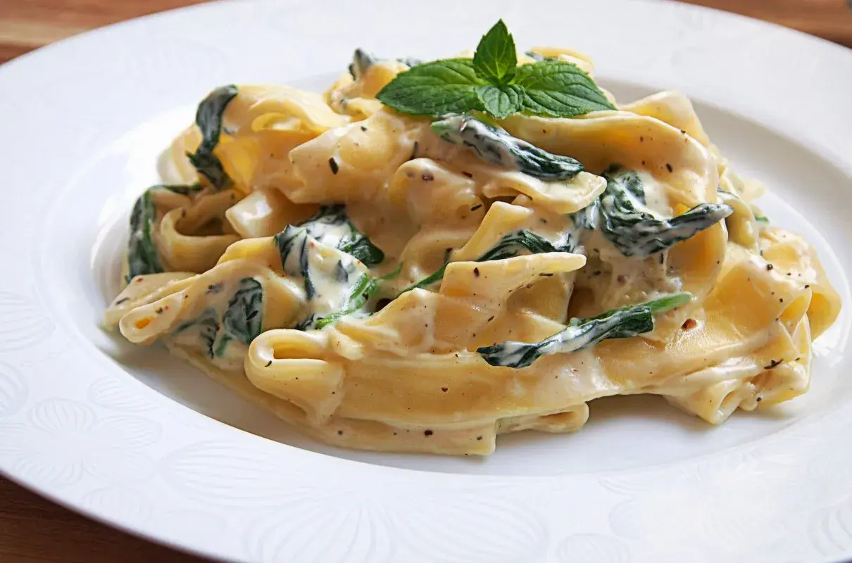 Pappardelle w kremowym sosie ze szpinakiem i mascarpone, udekorowane listkami mięty. Pyszne danie, które zachwyci każdego.