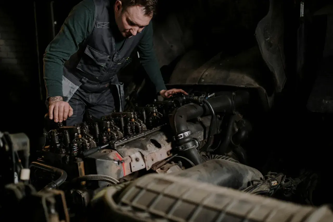 Mechanik w kamizelce pracuje nad silnikiem, wykonując odpowietrzanie silnika.