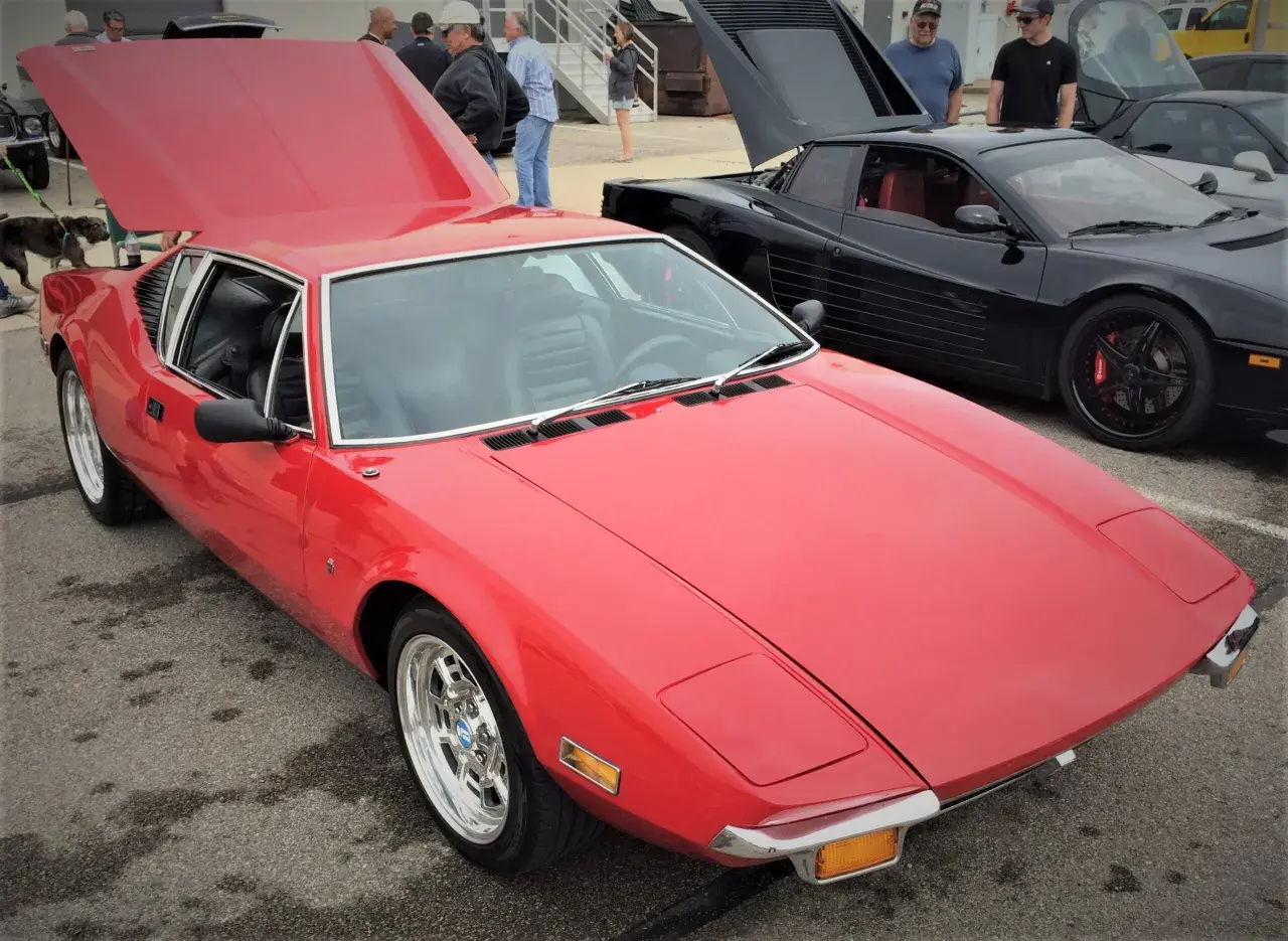 En röd De Tomaso Pantera bil med uppfälld huv. Bredvid står en svart bil med uppfällda dörrar.