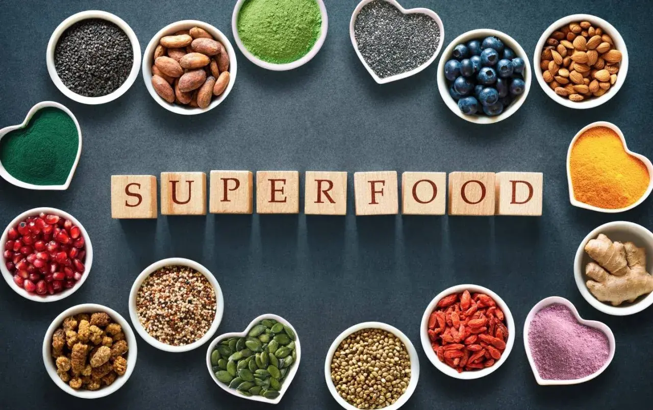 Scopri quali sono i superfood: semi di chia, mirtilli, mandorle, curcuma, zenzero, bacche di goji e altro ancora, disposti attorno alla parola "SUPERFOOD".
