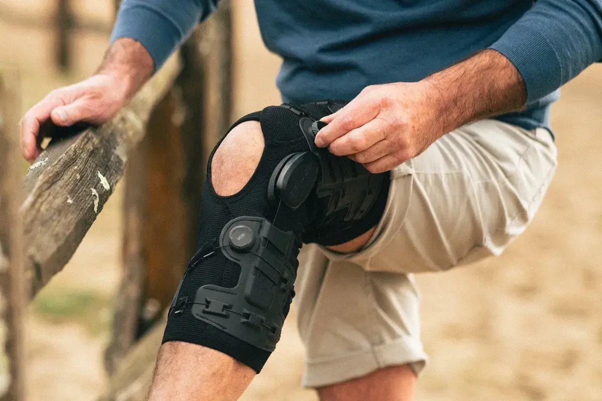 Mann legt eine DONJOY Schiene am Knie an. Die Schiene stützt das Bein für mehr Stabilität.