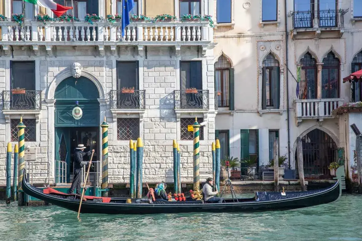 Gondola a Venezia, perfetta per un itinerario di un giorno. Un gondoliere guida la barca lungo un canale, con palazzi storici sullo sfondo.