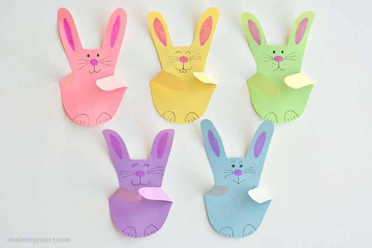 Fünf bunte Papierhasen, jeder ein einfacher hase, sitzen nebeneinander.