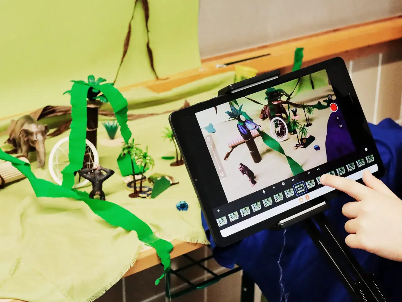 Kinder erstellen im Rahmen eines Stop Motion Projekts für die Grundschule eine Dschungelszene mit Spielzeugfiguren und bunten Kulissen.