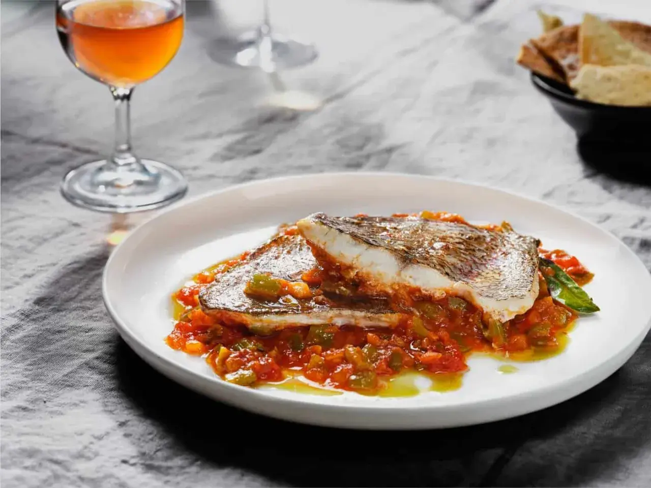 Delicioso plato de urta a la roteña, con pescado blanco y verduras en salsa, acompañado de una copa de vino.