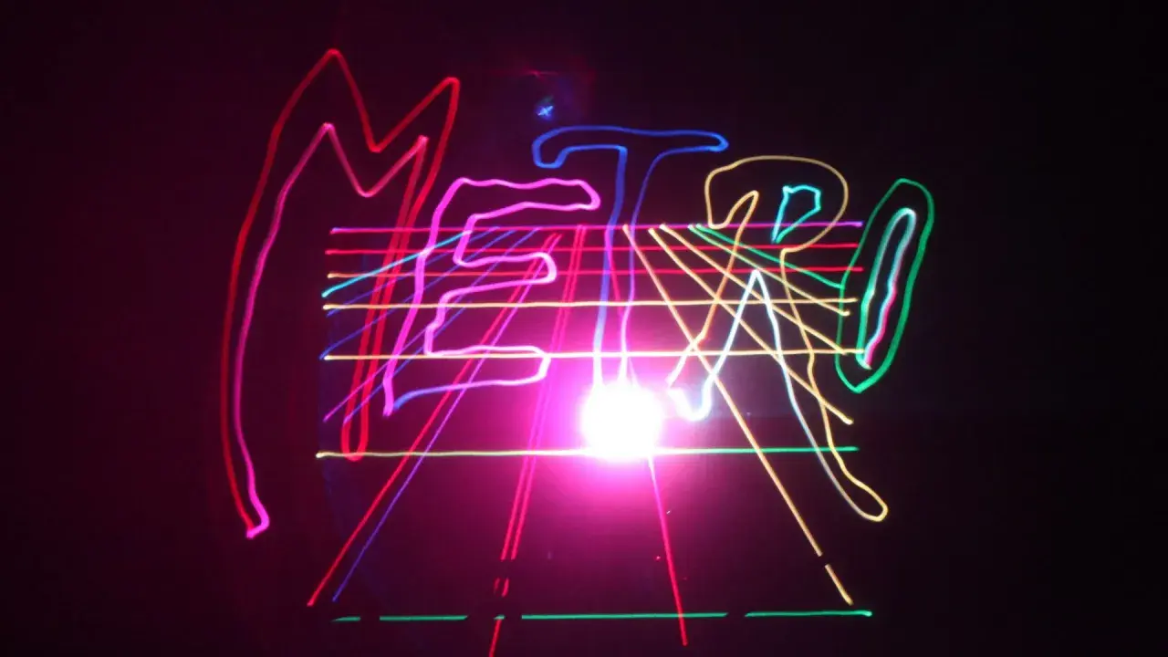Kolorowe, neonowe linie tworzą napis "METRO" na czarnym tle, przypominając o energetycznym, musical metro.