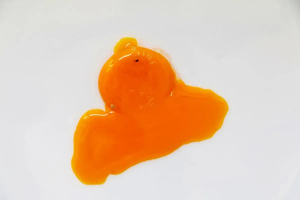 Un œuf rouge, éclatant sur une surface blanche, sa texture liquide et vibrante évoque une œuvre d'art abstraite.