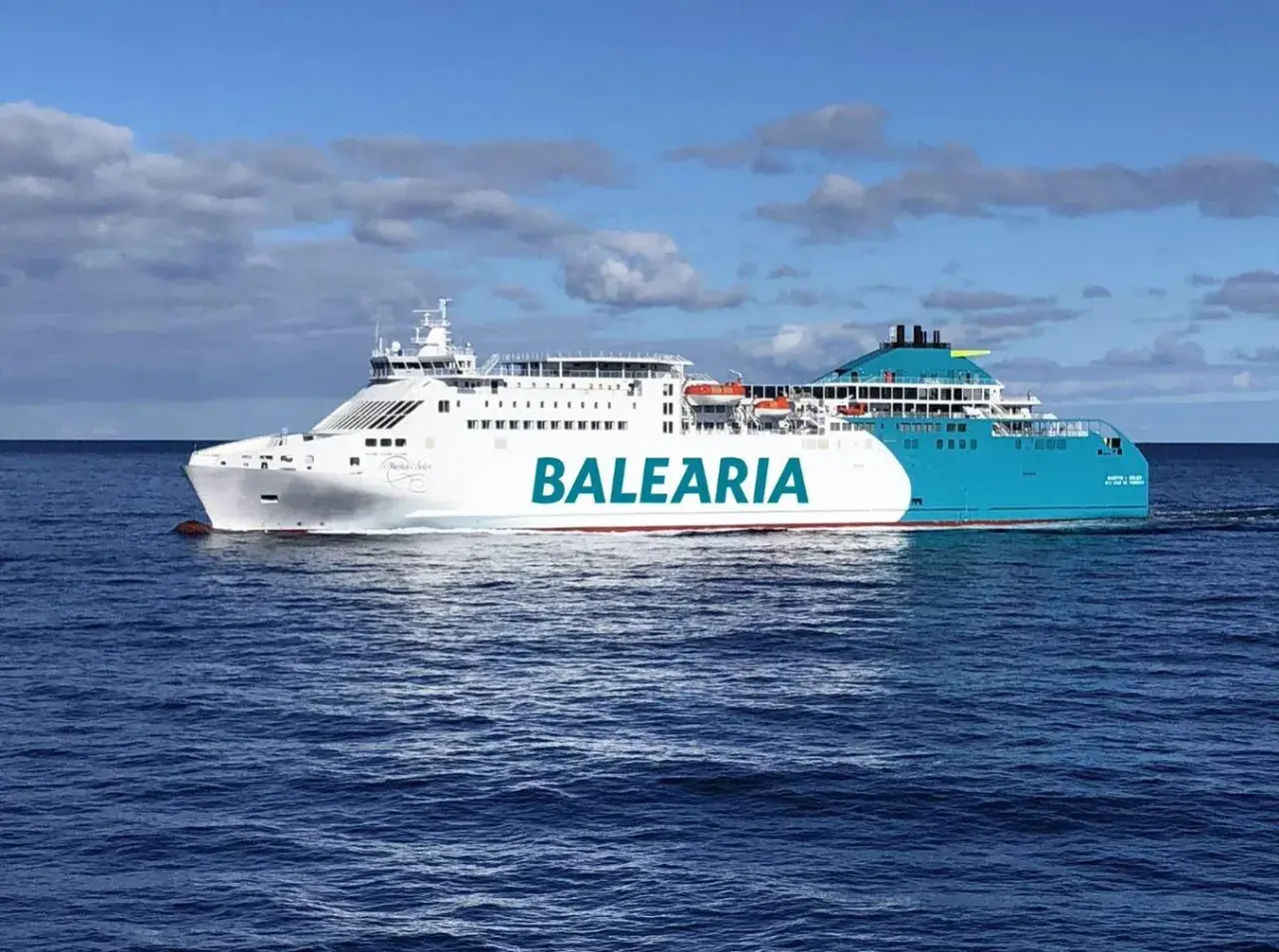 Un gran barco de Baleària navega por el mar azul, rumbo a Mallorca desde Valencia.