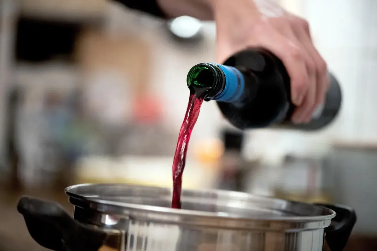 Rotwein wird in einen Topf gegossen. Beim Kochen verdunstet Alkohol.