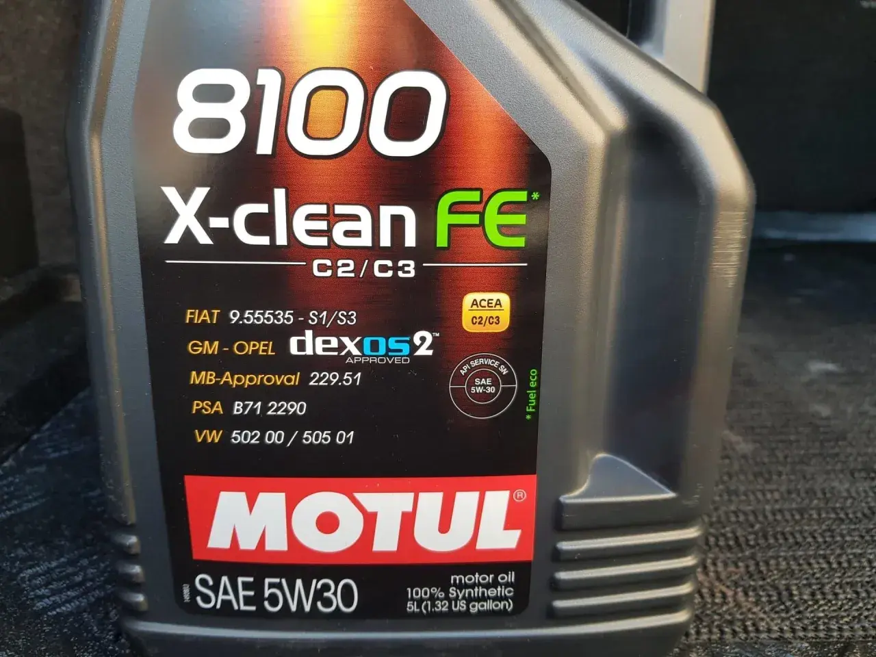 Czarna butelka oleju silnikowego Motul 8100 X-clean FE 5W30 z widocznymi specyfikacjami.