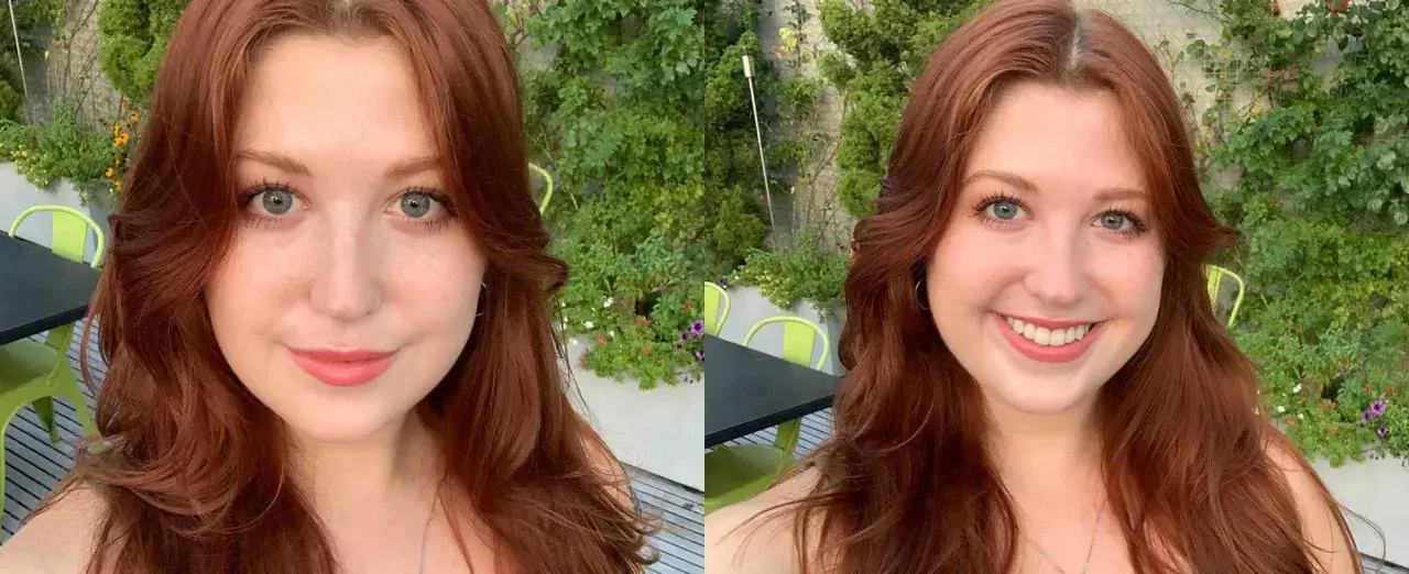 Mujer con cabello largo y ondulado en tonos tinte pelirrojo, ojos azules y pecas, sonríe en un entorno exterior con vegetación.