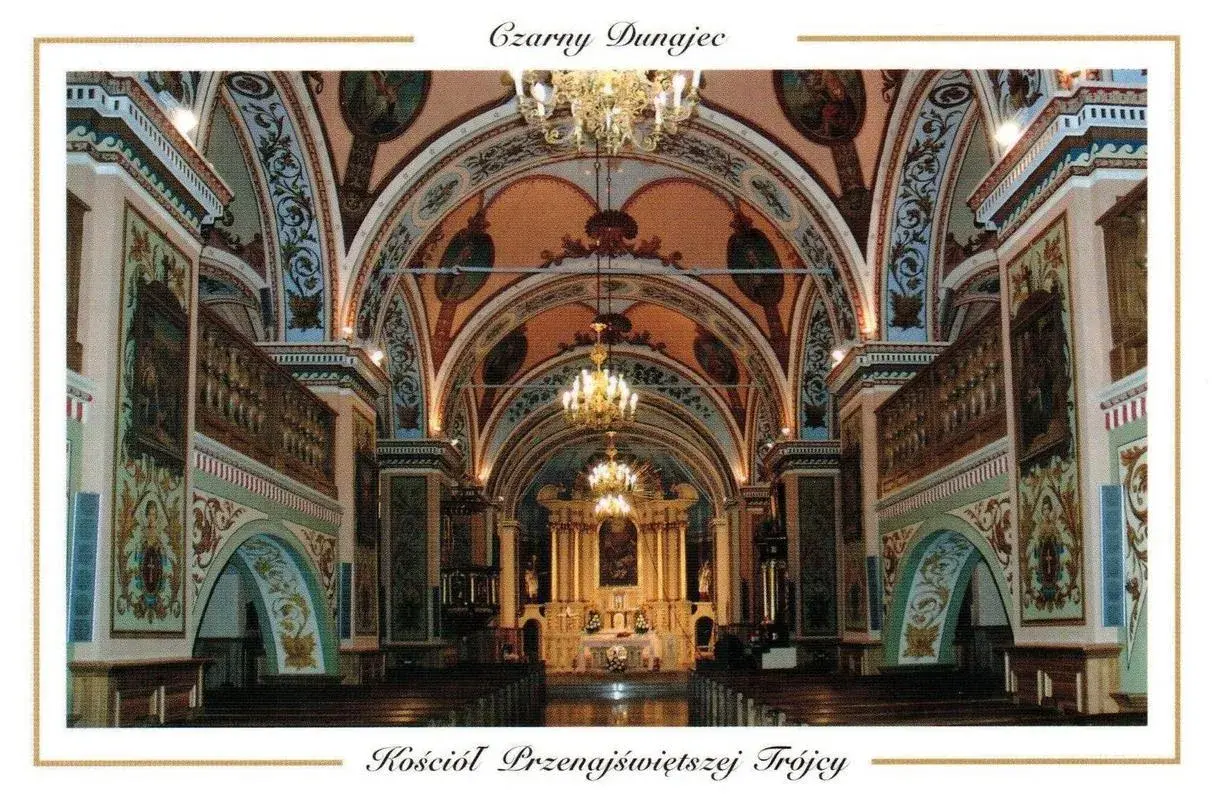 Wnętrze kościoła Przenajświętszej Trójcy w Czarnym Dunajcu. Bogato zdobione sklepienia, ołtarz i ławy tworzą uroczystą atmosferę.