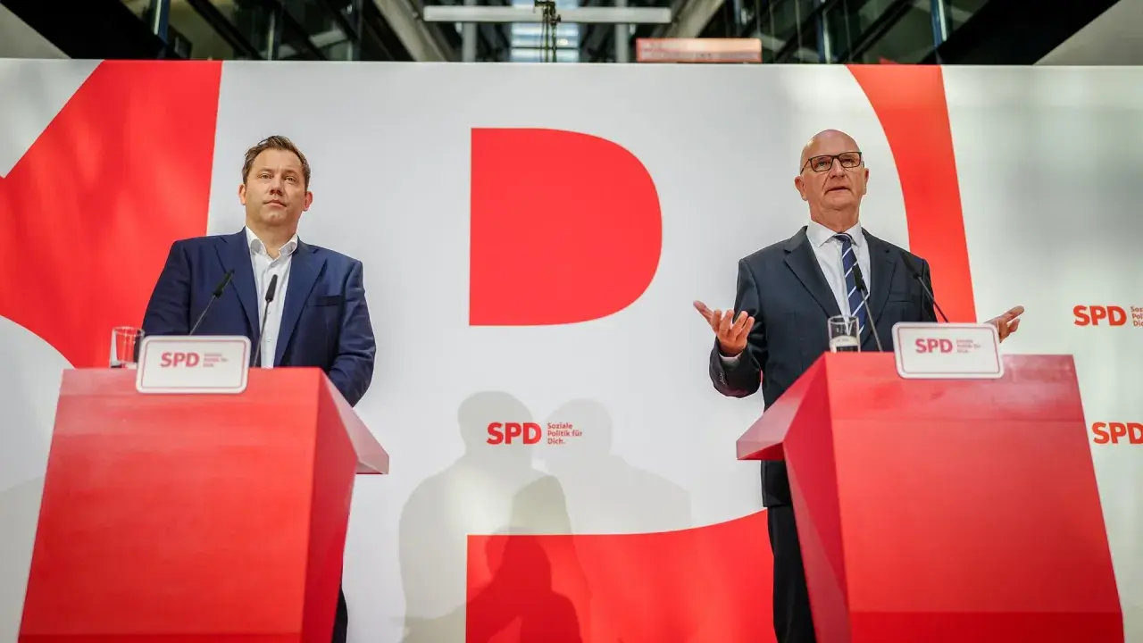 Zwei Männer stehen an roten Rednerpulten vor einer großen roten "D"-Grafik. Sie sprechen über das wahlergebnis brandenburg.