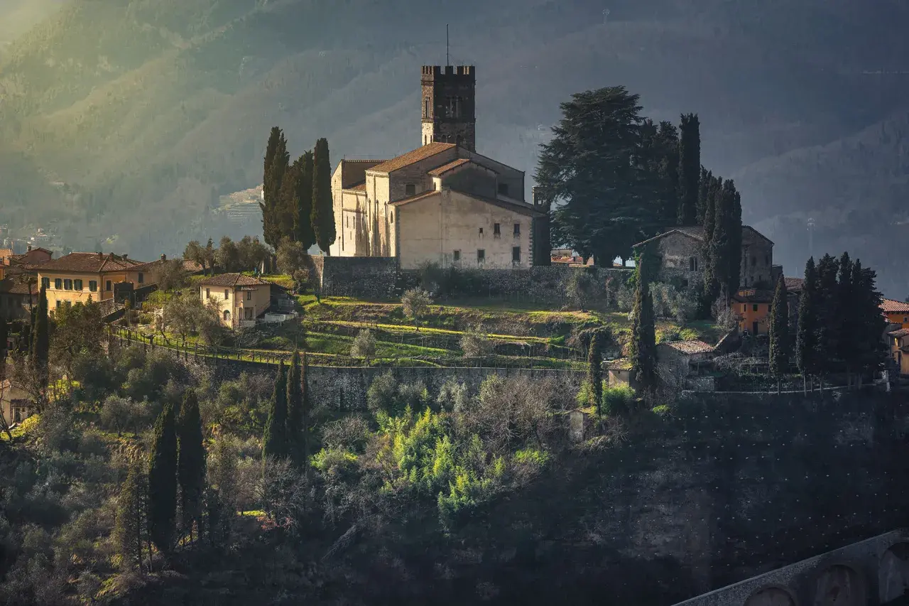 Borgo medievale in collina, con chiesa e torre, ideale per un giro in moto nella Garfagnana.