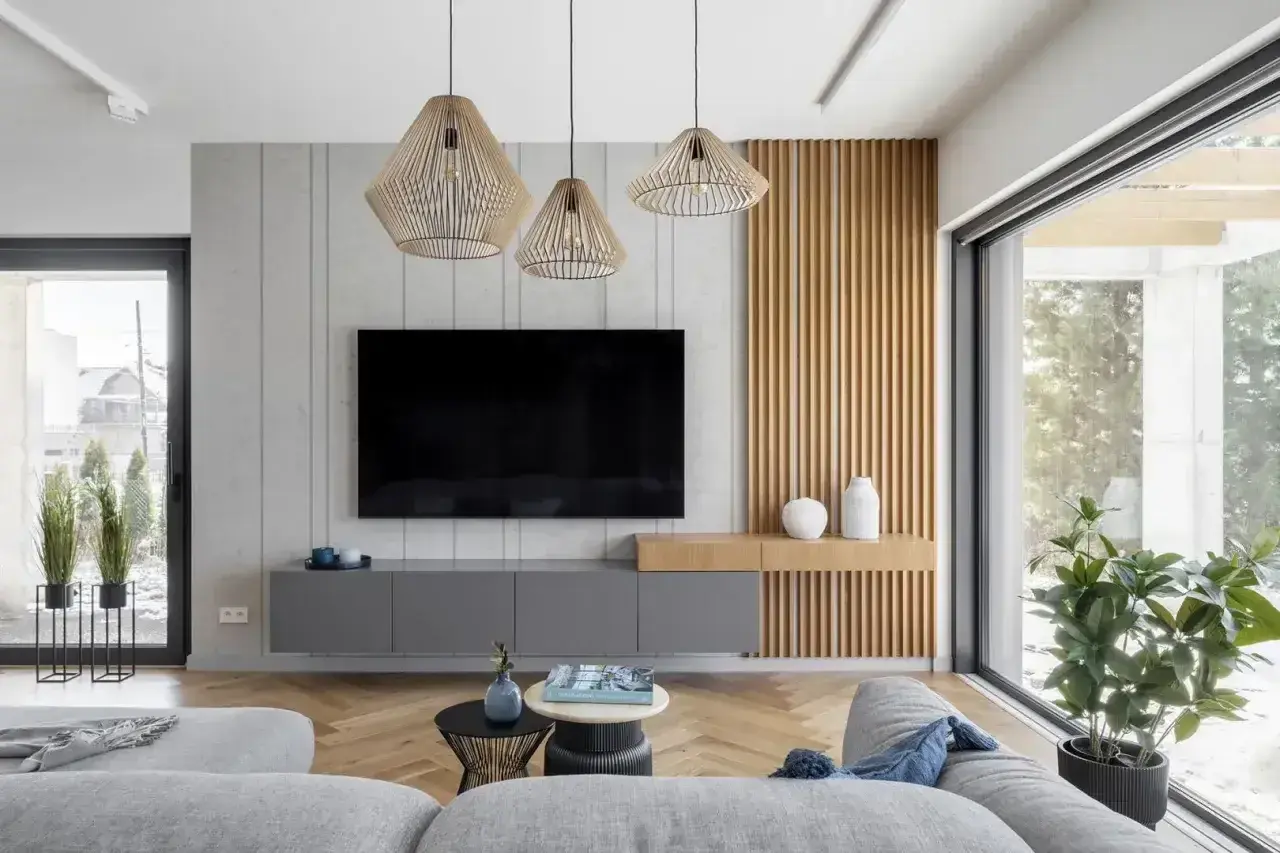 Nowoczesny salon z szarymi meblami i drewnianymi panelami. Trzy wiszące lampy tworzą przytulną atmosferę, idealną do relaksu. Zastanawiasz się, ile lumenów do salonu?