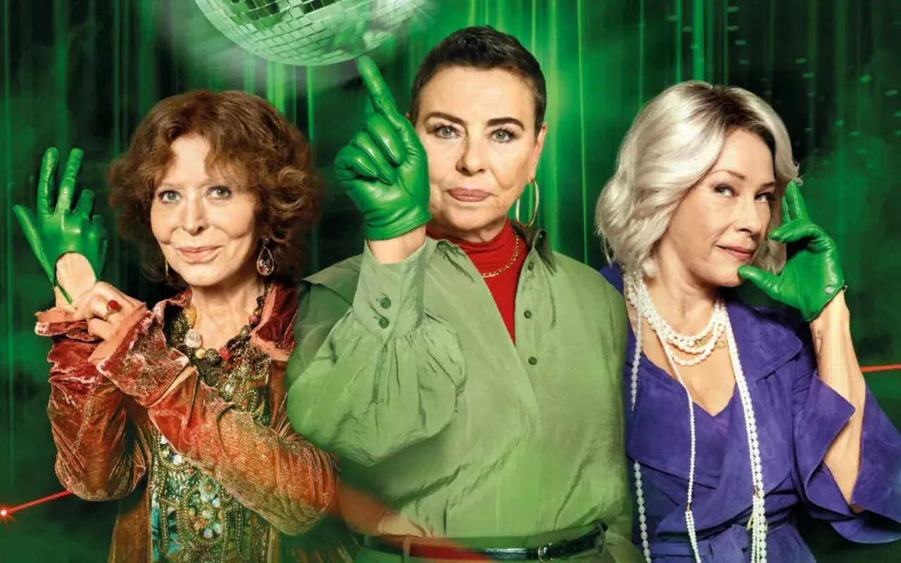 Trzy kobiety w zielonych rękawiczkach, tworzące gang, pozują na tle dyskotekowej kuli.