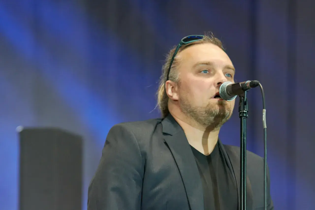 Wojciech Cugowski śpiewający do mikrofonu w czarnej marynarce.