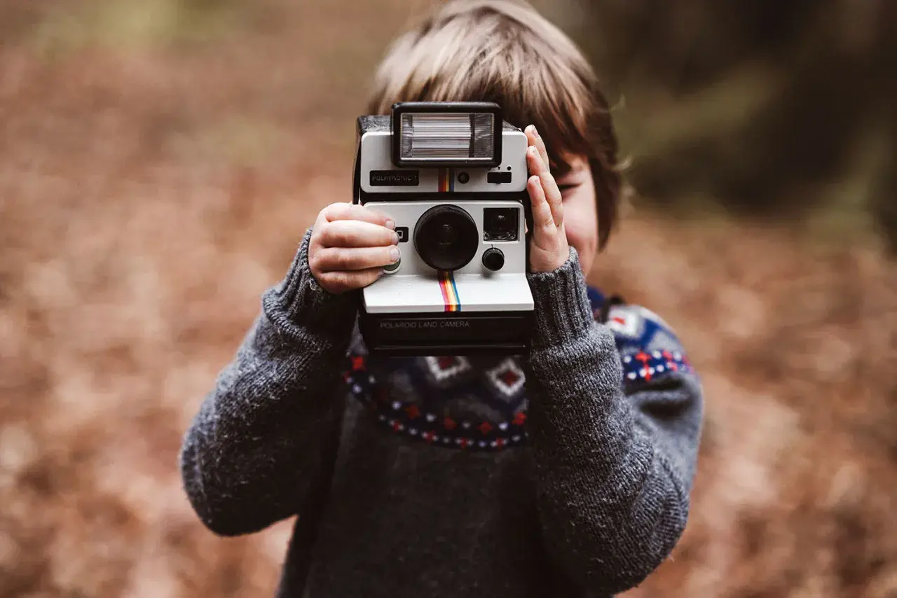 Dziecko z aparatem Polaroid Land Camera, gotowe do uchwycenia magicznych chwil.