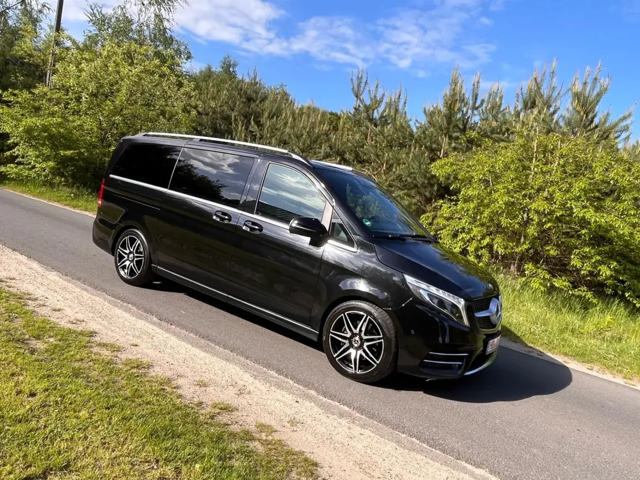 Czarny Mercedes-Benz V-klasa na drodze wśród zieleni.