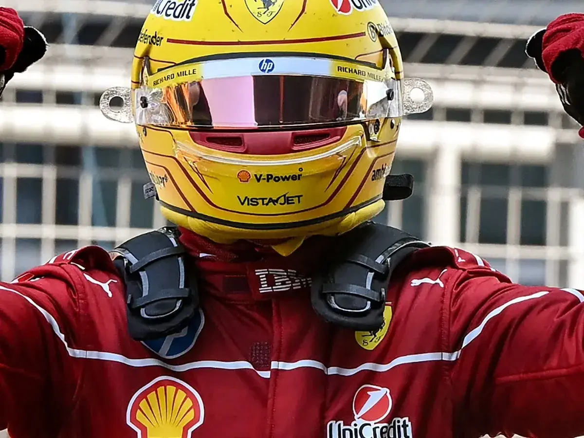 Sir Lewis Hamilton feiert in seinem gelben Ferrari-Helm und rotem Rennanzug einen Sieg.