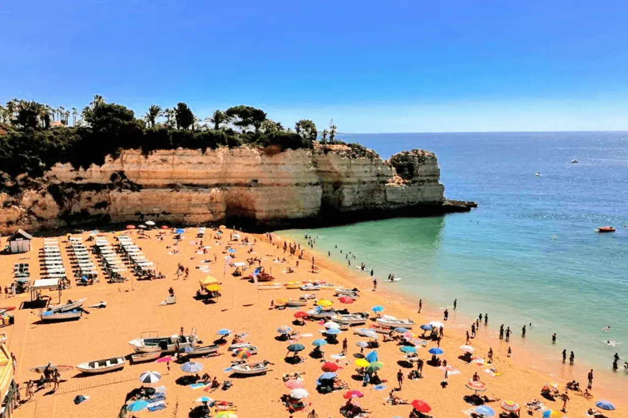 Playa con gente disfrutando del sol y el mar. Un día perfecto para actividades en el Algarve.