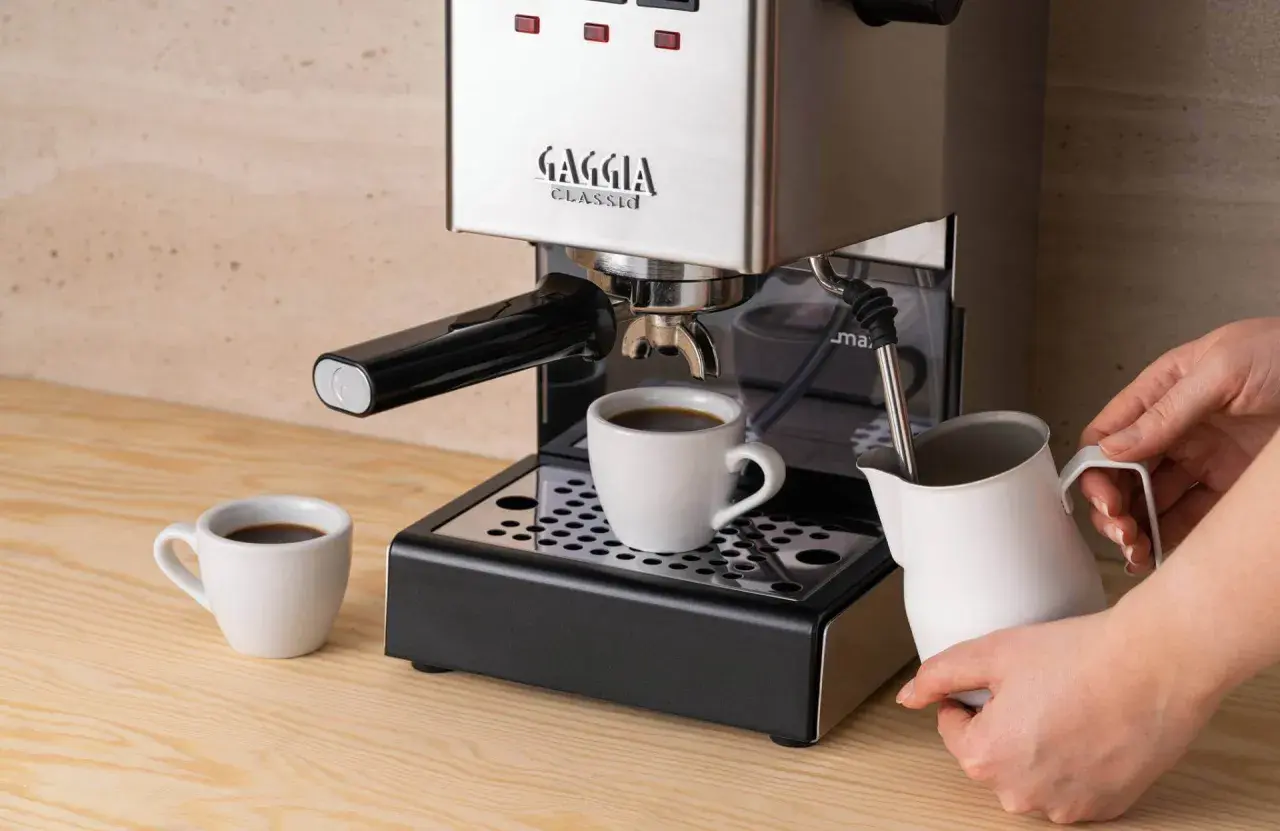 Gaggia Classic w rankingu ekspresów do kawy do 2000 zł. Parzy kawę do filiżanki, obok dzbanek na mleko.