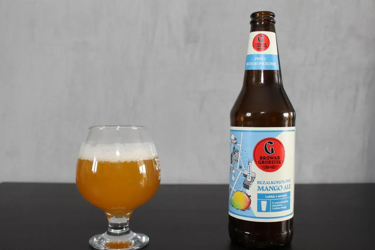 Szklanka z bursztynowym piwem i butelka bezalkoholowego mango ale Browaru Grodzisk.